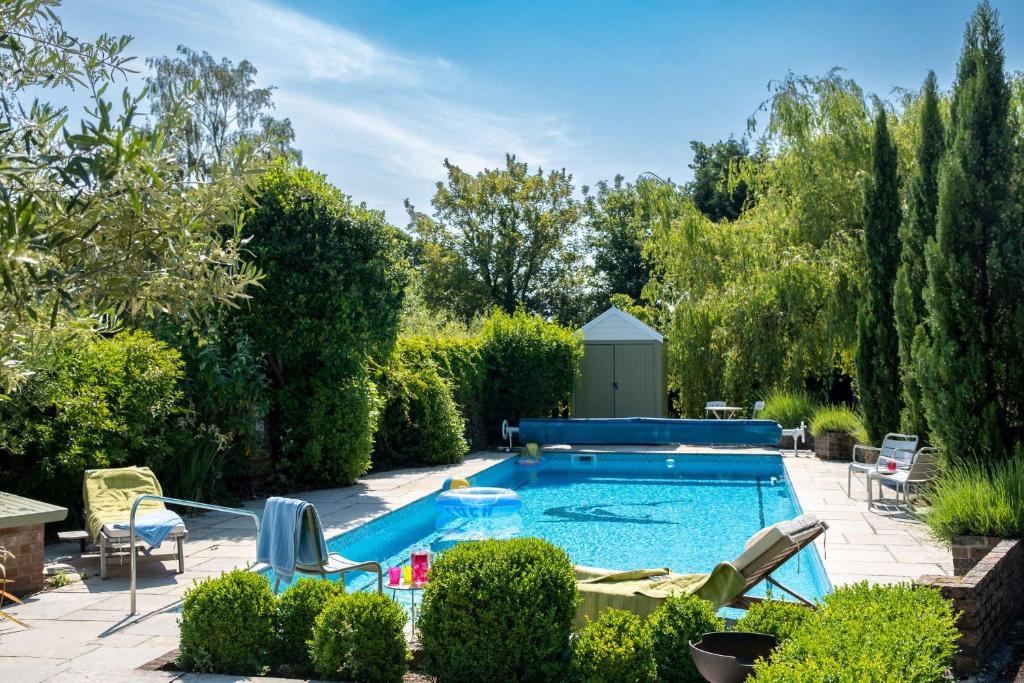 una piscina en un patio con sillas y árboles en The Lodge en New Milton