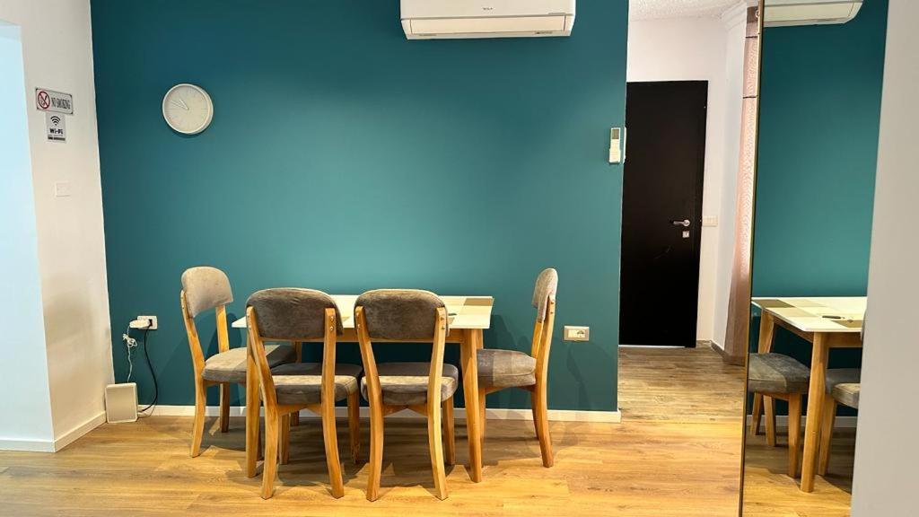 een eettafel met stoelen en een blauwe muur bij Host Elios Tirana in Tirana