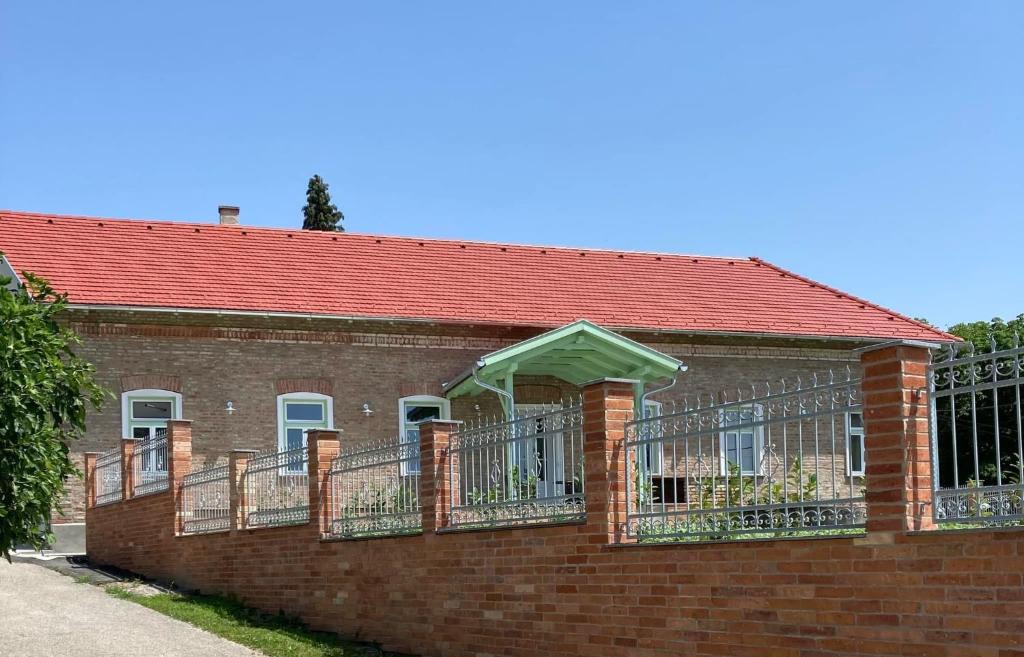 a brick building with a red roof and balcony at Kira Panzió in Lengyeltóti