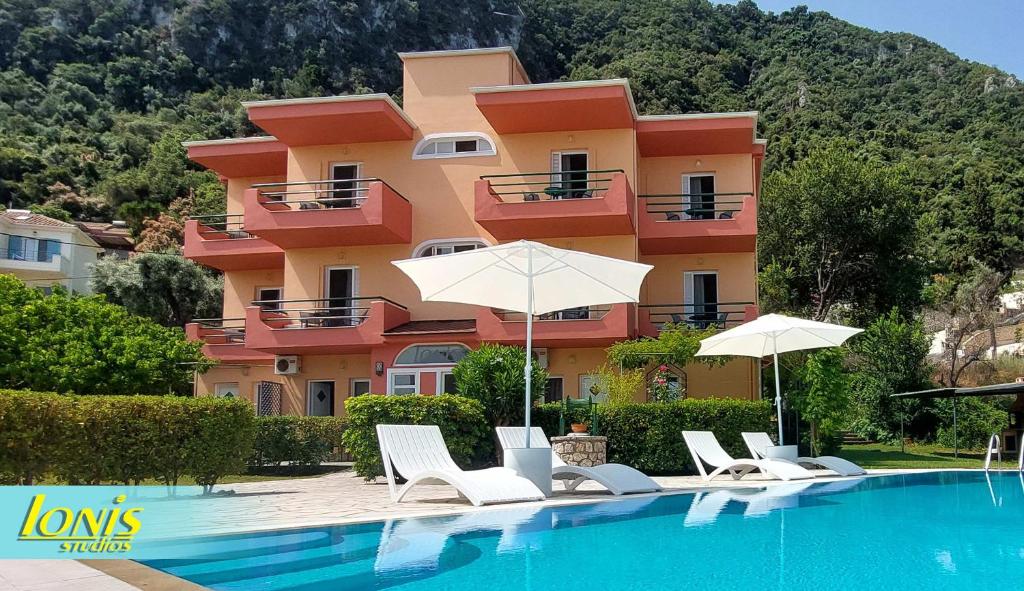 a building with chairs and umbrellas next to a swimming pool at Ionis Studios in Lefkada Town