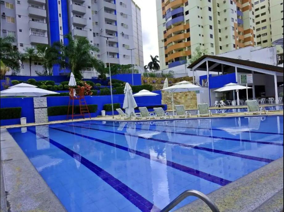 a large blue swimming pool with chairs and umbrellas at Residencial Thermas Rio Caldas in Caldas Novas
