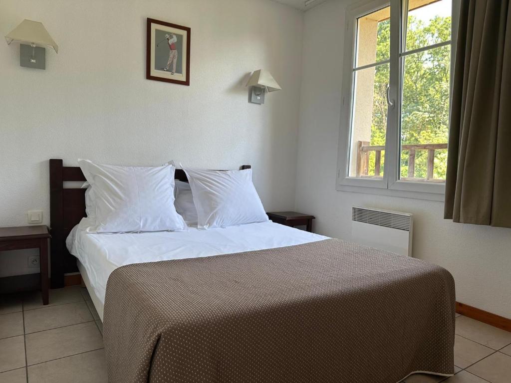 a bedroom with a bed with white sheets and a window at Le Green in Levernois