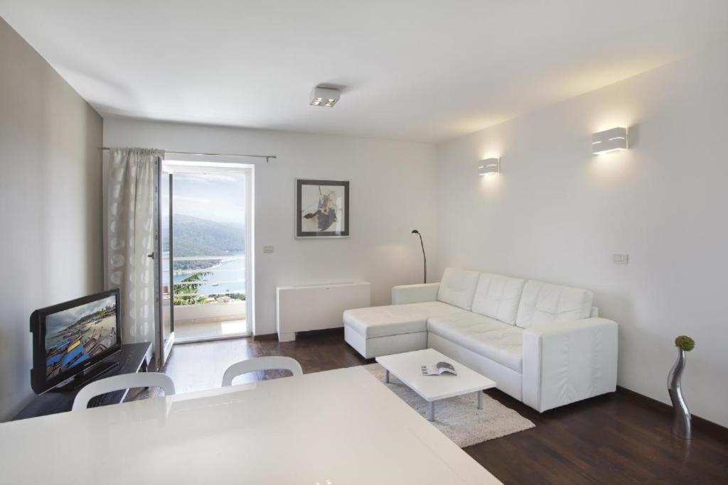 a living room with a white couch and a tv at Casa M Rabac in Rabac