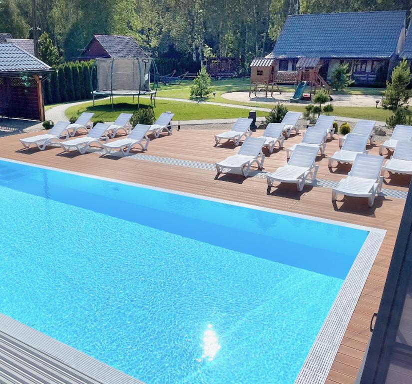 a swimming pool with chaise lounge chairs and a group ofvisor at Domki Zalesie in Jarosławiec