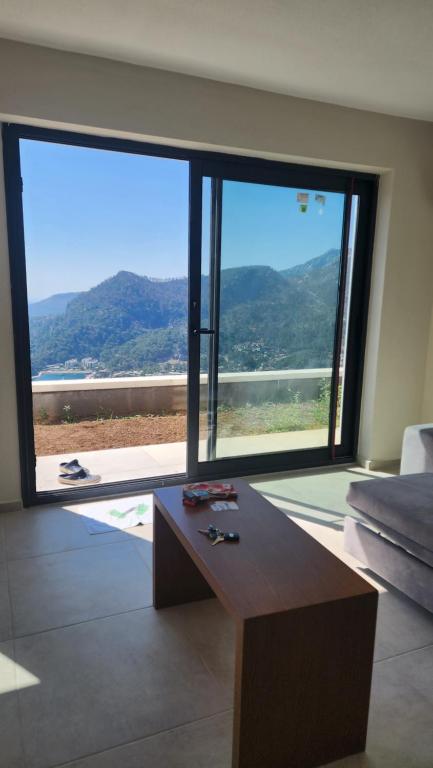 a living room with a table and a large window at Turunç muhteşem manzaralı yeni bina in Marmaris