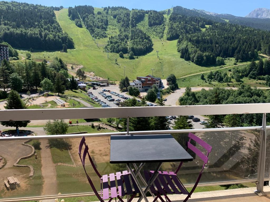 une table et des chaises sur un balcon avec vue sur une montagne dans l'établissement Avec balcon, au pied des pistes et randos, à Villard-de-Lans