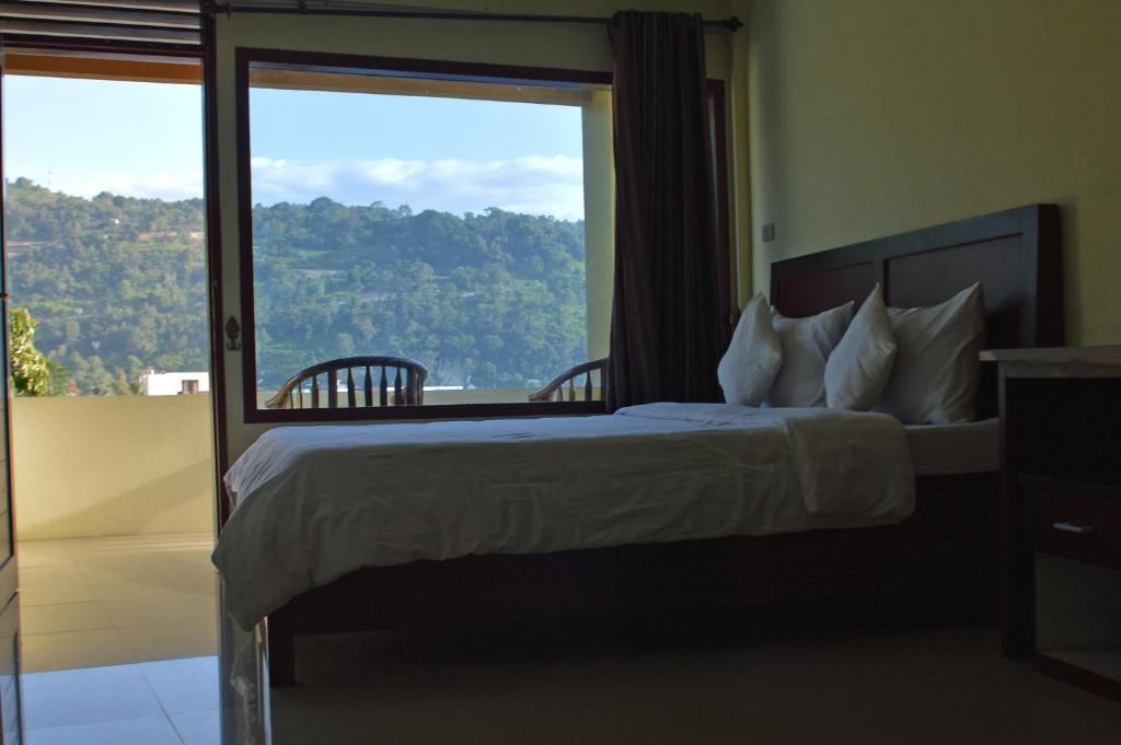 a bedroom with a bed and a large window at Hotel Toba Shanda By Helocus in Parapat