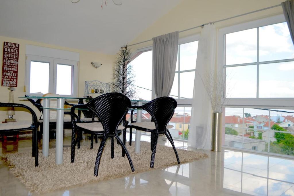 comedor con 3 sillas, mesa y ventanas en Wohnung mit Meerblick Romy, en Preko