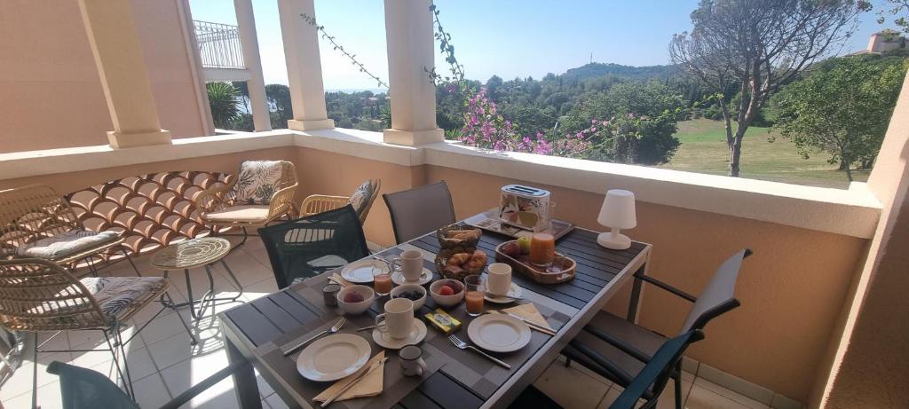 a table with plates of food on a balcony at Agay Cap Esterel Village Allée Fleurs - F2 Clim vue golf et mer - Grande terrasse plein sud in Agay - Saint Raphael