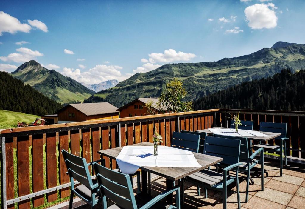 2 tafels en stoelen op een balkon met uitzicht op de bergen bij Pension Uga in Damuls