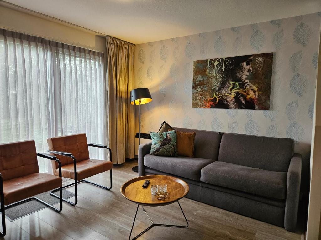 un soggiorno con un divano, sedie e un tavolo di De Kapershut a Hollum