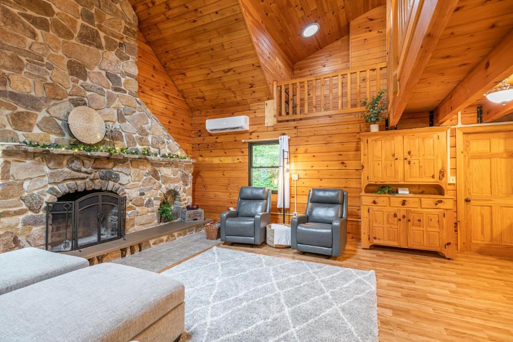 a living room with a stone fireplace and two chairs at Creekside Hideaway in Reedsville