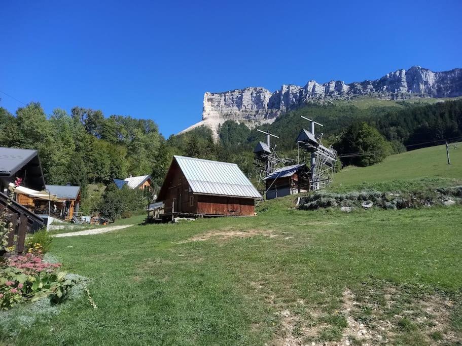 a field with a barn with a mountain in the background at Appartement des cimes du Granier in Les Déserts
