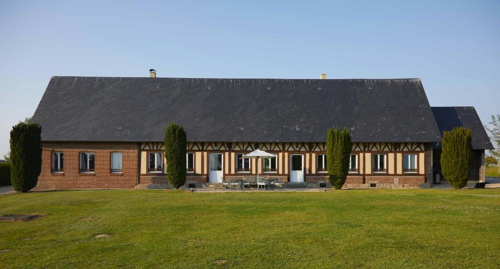 ein großes Backsteinhaus mit schwarzem Dach in der Unterkunft La Maison de Charlotte in Doudeville