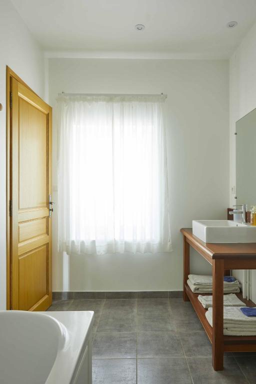 a bathroom with a tub and a sink and a window at La Maison de Charlotte in Doudeville