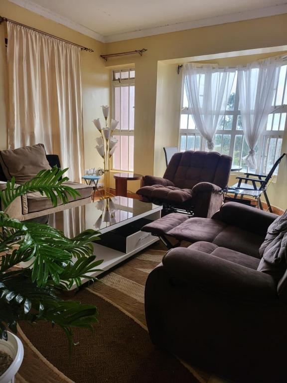 - un salon avec des canapés, des chaises et des fenêtres dans l'établissement G&G Westindies Executive One Bedroom, à Eldoret