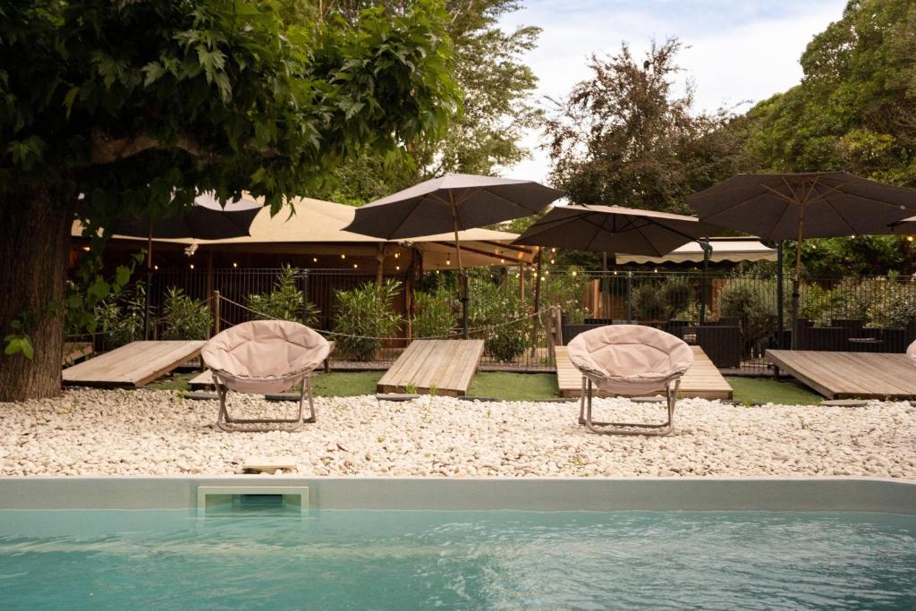 a group of chairs and umbrellas next to a pool at SUZE LUXE NATURE in Suze-la-Rousse