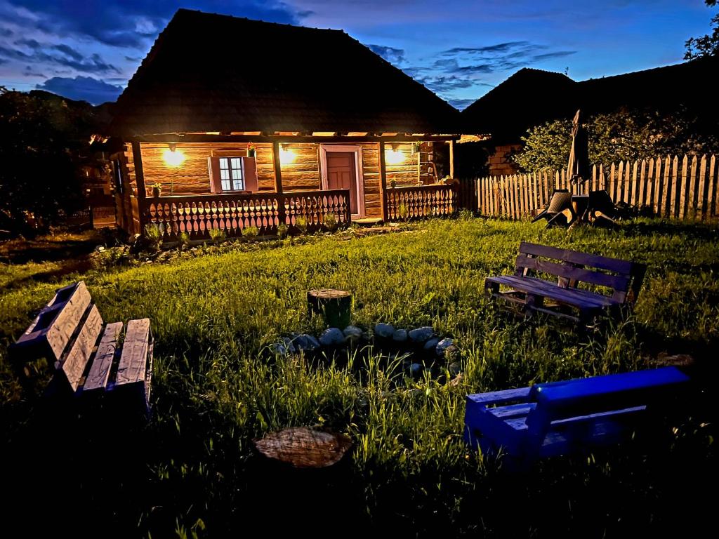 una cabaña de madera con dos bancos en el patio en Casa cu Lavanda, en Petroşani
