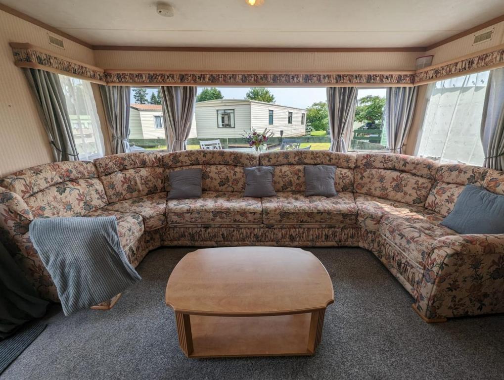 a living room with a large couch and a table at 30 Glenfinart Caravan Park in Dunoon