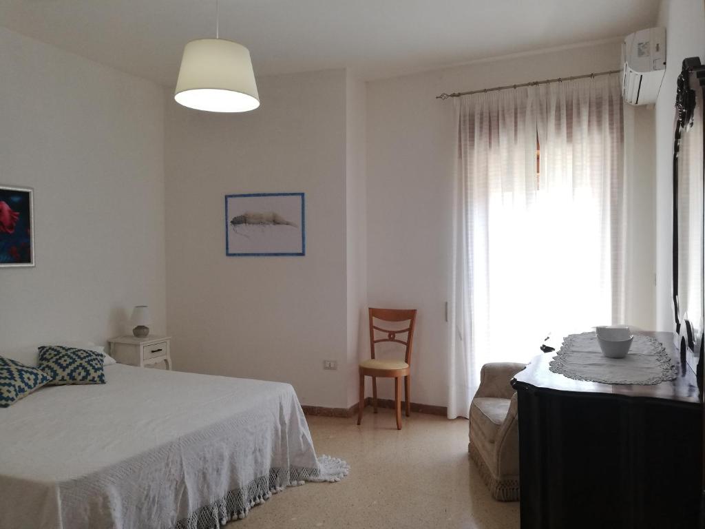 a bedroom with a bed and a chair and a window at Dimora d'artista in Galatone