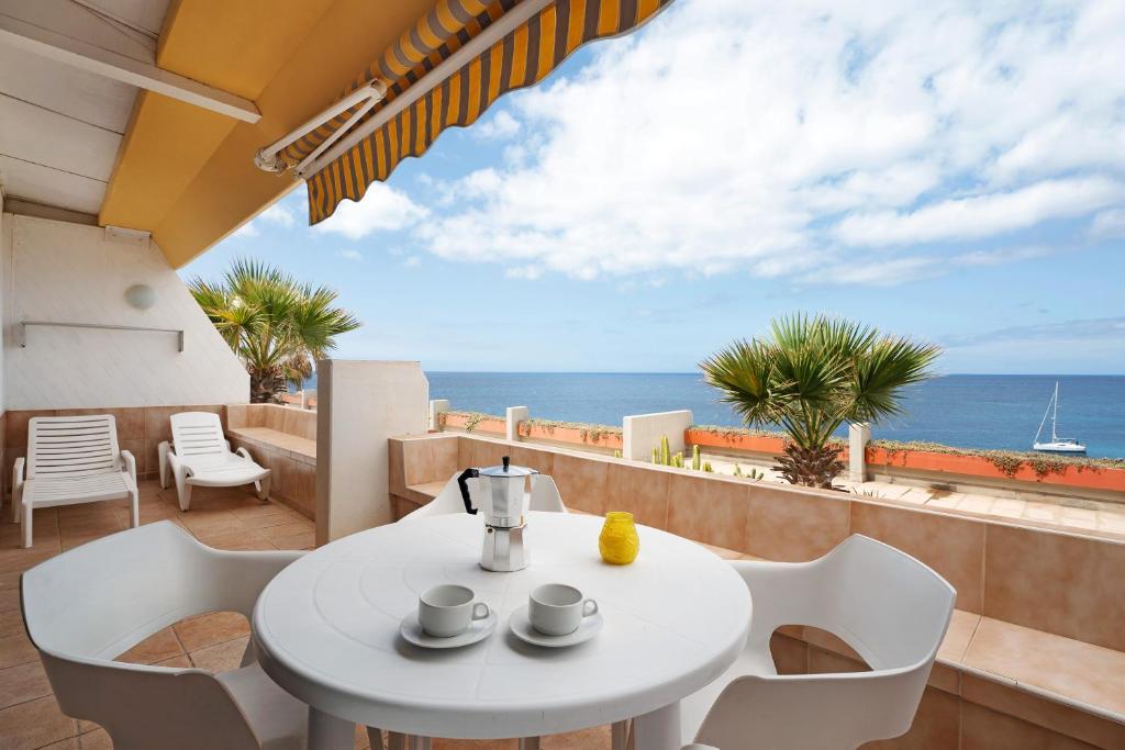 stół i krzesła na balkonie z widokiem na ocean w obiekcie Maravilla Over the Ocean w mieście Costa Del Silencio