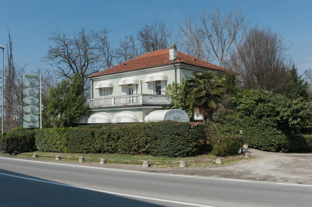 a white house with a balcony on the side of a road at Hotel Villa Giulia in Tortona