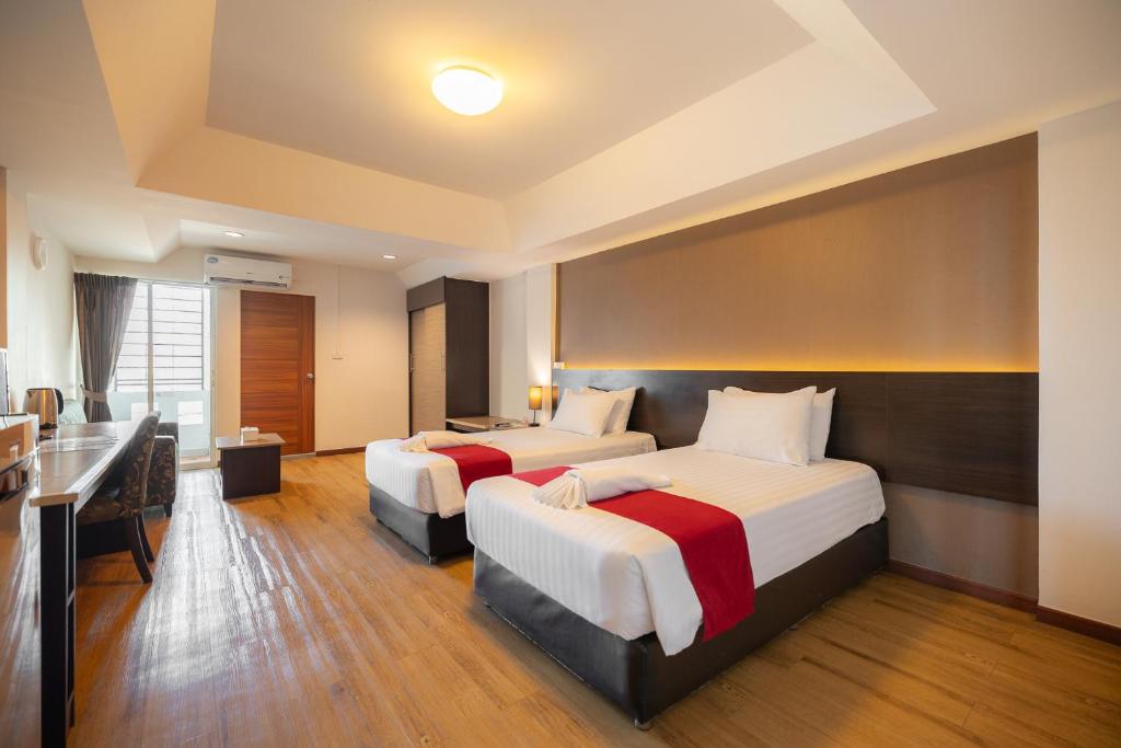 ラートクラバンにあるゴールデン ジェイド スワンナプームのベッド2台とデスクが備わるホテルルームです。
