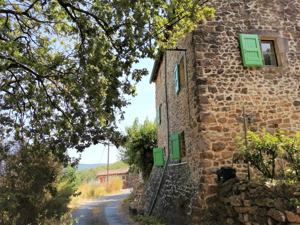 un bâtiment en pierre avec des volets verts sur une route dans l'établissement Proche baignade, La Bergerie de Claire, à Thoiras