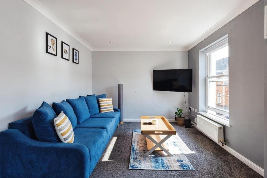 ein Wohnzimmer mit einem blauen Sofa und einem TV in der Unterkunft Stunning Refurbished Apartment in Central Cheltenham inc. Parking in Cheltenham