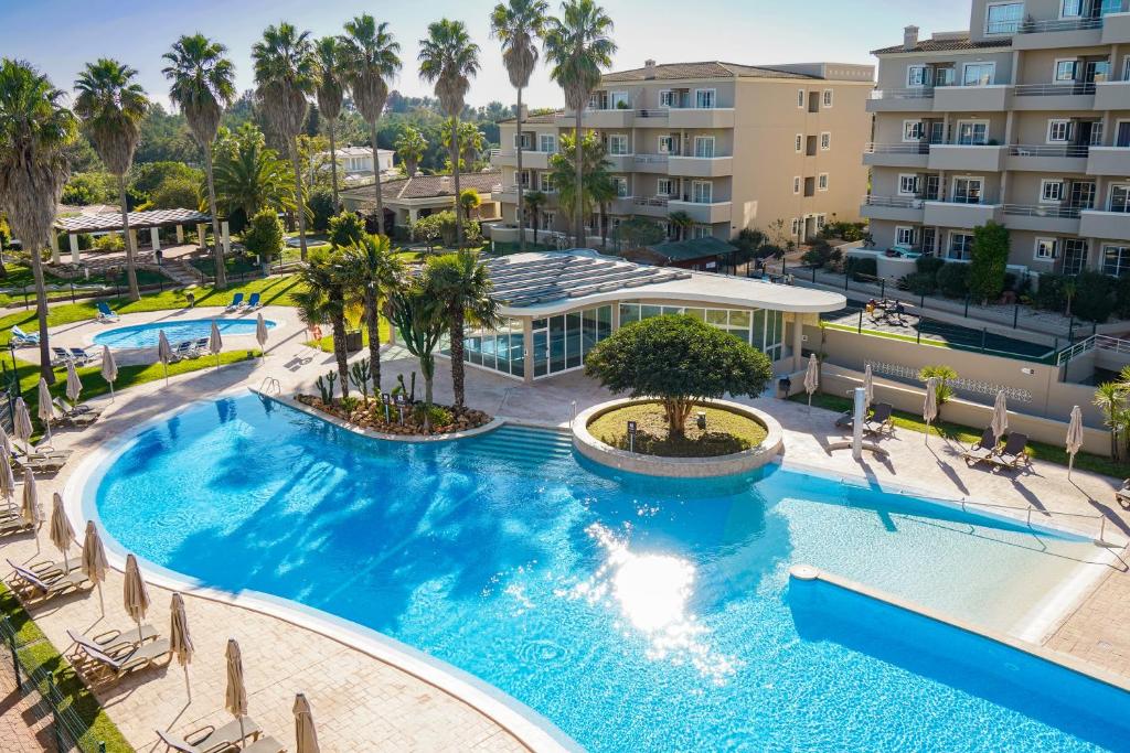- une vue sur la piscine bordée de palmiers et de bâtiments dans l'établissement Vitor's Plaza, à Portimão