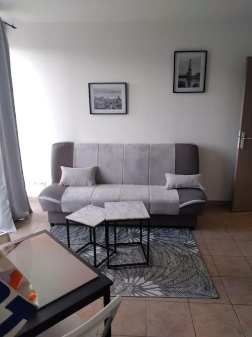 a living room with a couch and two tables at Appartement proche Disney Paris in Montévrain