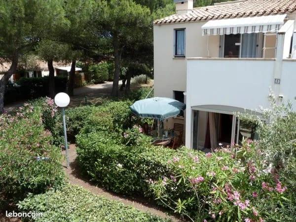 une maison avec un parapluie bleu et quelques buissons dans l'établissement T2 luxe rdj cap d agde, au Cap d'Agde