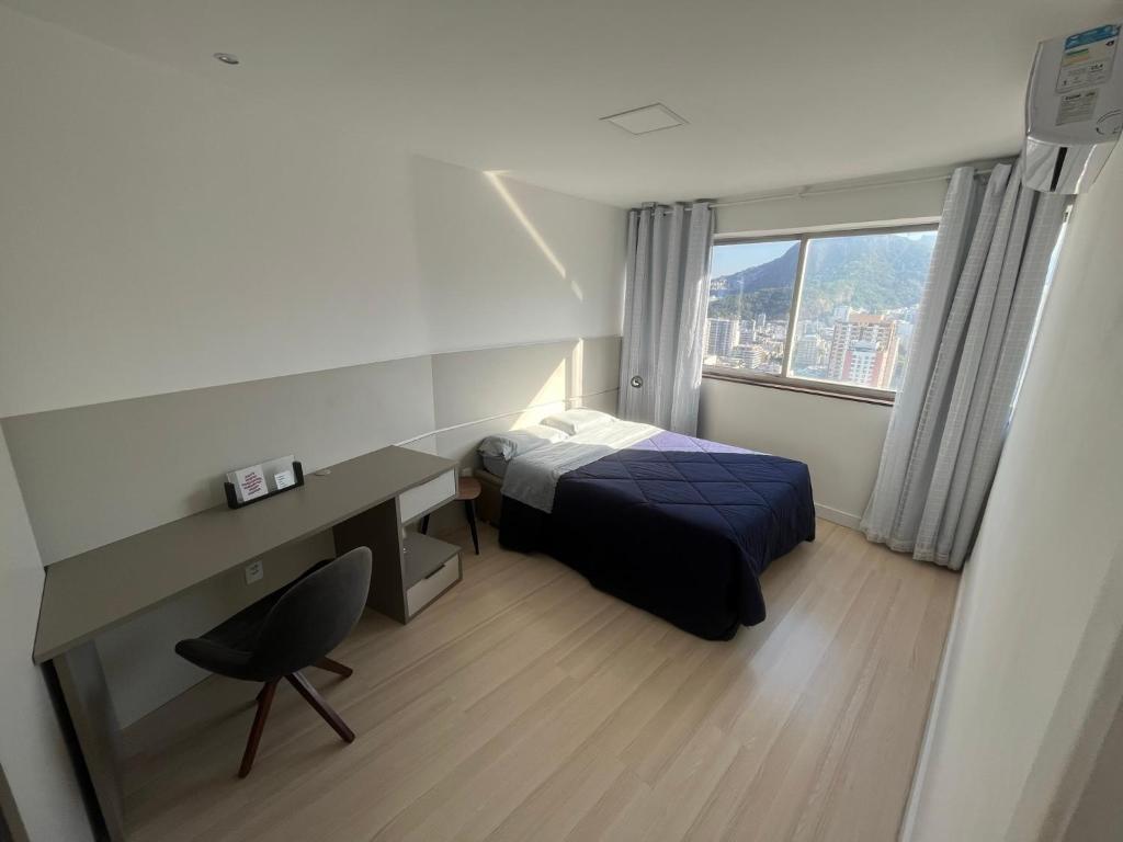 a bedroom with a bed and a desk and a window at Apartamento com Vista Imperdível in Rio de Janeiro