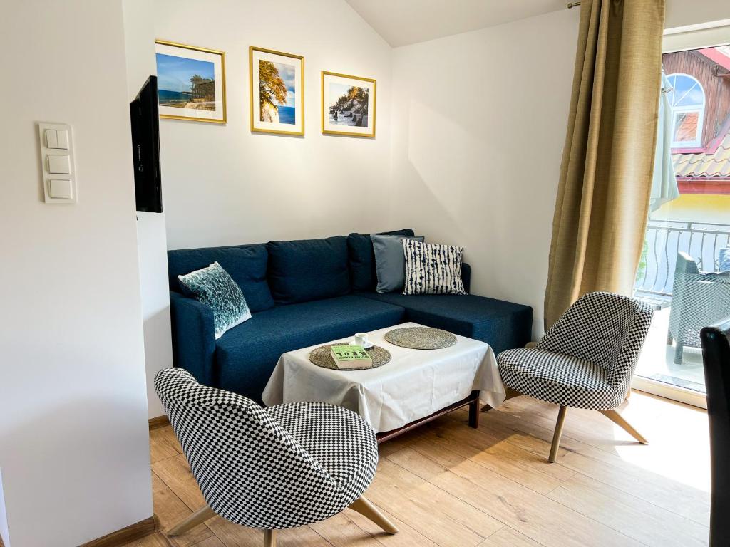 a living room with a blue couch and chairs at Apartamenty Zacisze 1 in Poddąbie