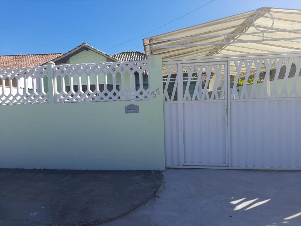 a white fence with a gate in front of a house at Linda casa pertinho da Lagoa in Iguaba Grande