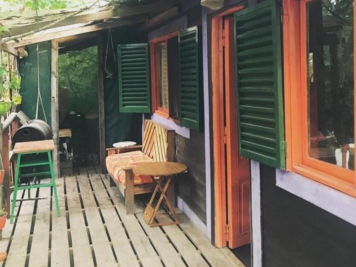 un porche de una casa con ventanas verdes y una mesa en Cabañas Verdes en Tigre