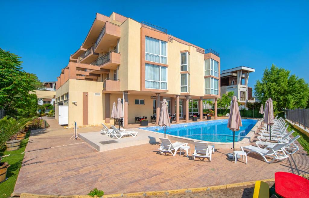 un edificio con una piscina con sillas y sombrillas en Aparthotel Royal Marina Beach, en Chernomorets
