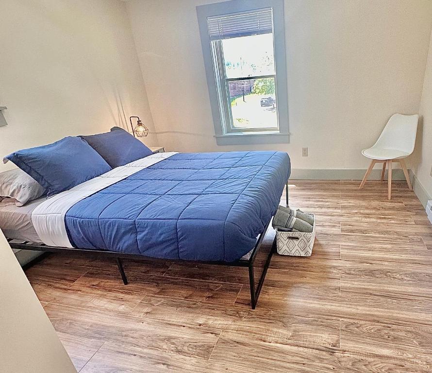 Schlafzimmer mit einem Bett mit blauer Bettwäsche und einem Fenster in der Unterkunft 2BR Sunshine Town Condo in Newport