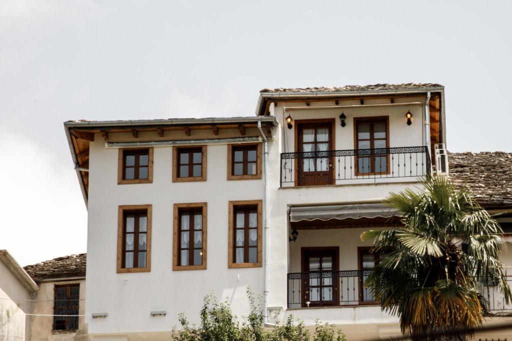 een wit gebouw met ramen en een palmboom bij Hotel Sarajet 1821 in Gjirokastër