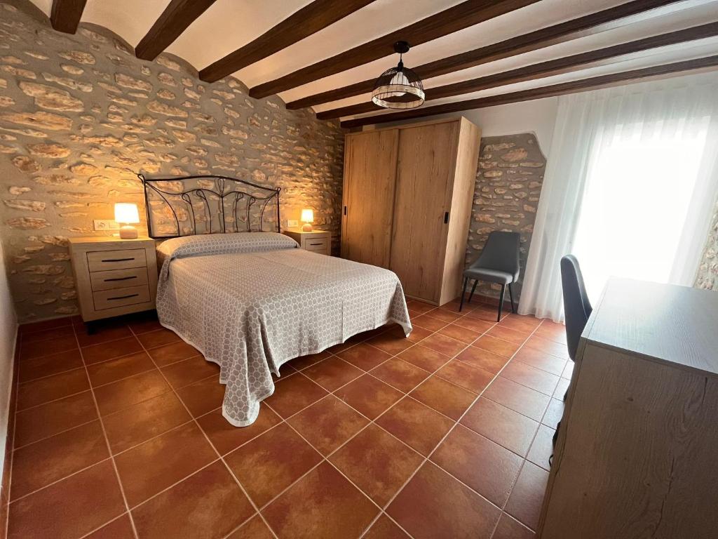 een slaapkamer met een bed en een stenen muur bij Ca la Beata in Cálig