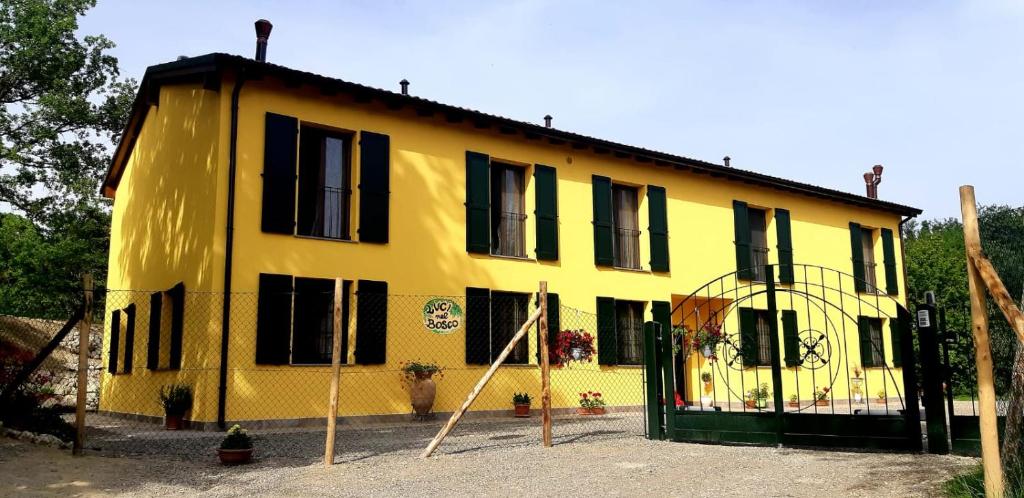 a yellow house with black windows and a fence at Luci nel Bosco 