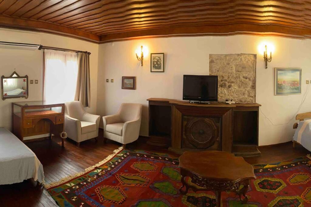 1 dormitorio con 1 cama, escritorio y TV en Cunda adasında rum evi, en Ayvalık