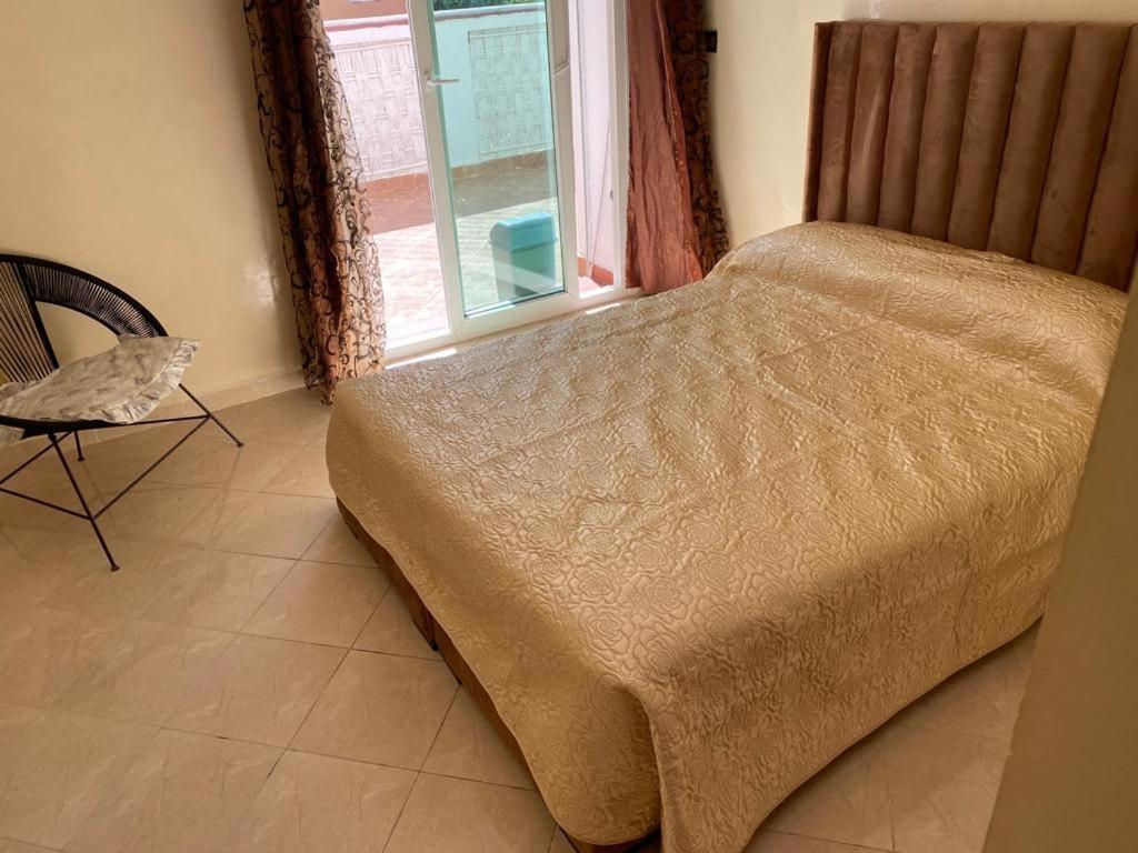 1 dormitorio con 1 cama, 1 silla y 1 ventana en Appartement avec piscine Mohamedia 2chambres, en Mohammedia