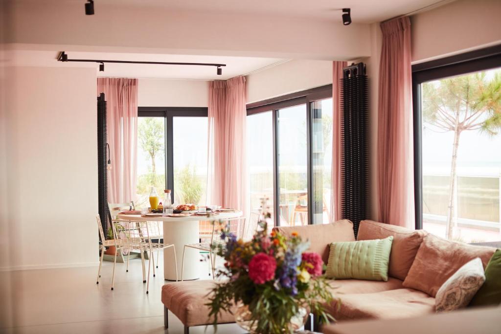 un salon avec un canapé et une table avec des fleurs dans l'établissement The Pink Penthouse, à La Panne