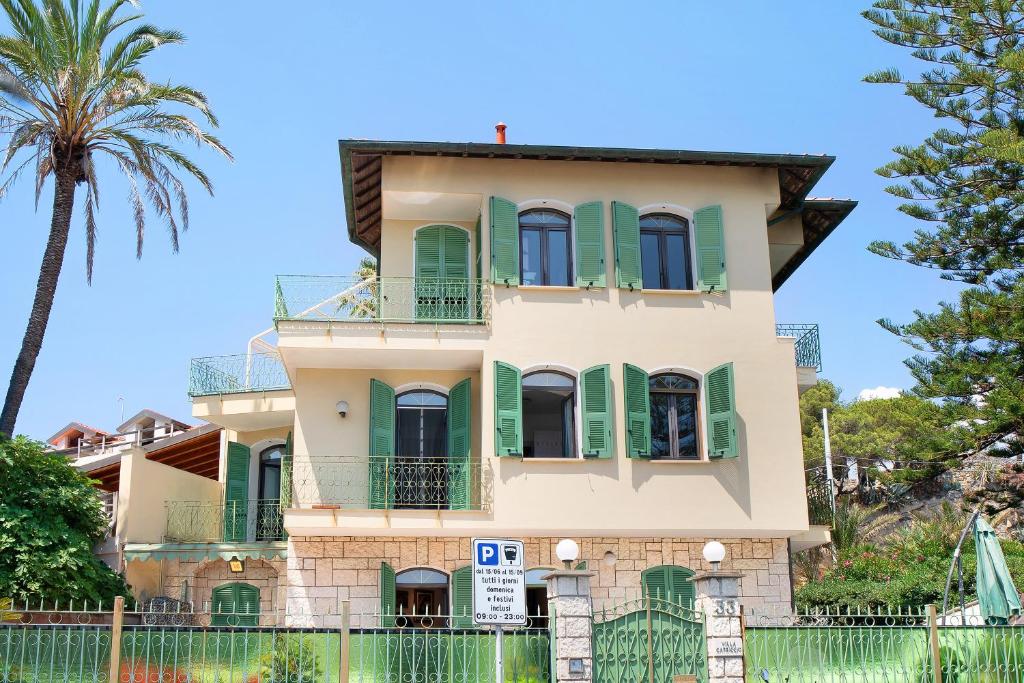 une maison avec des volets verts et un palmier dans l'établissement Capriccio, à Bordighera