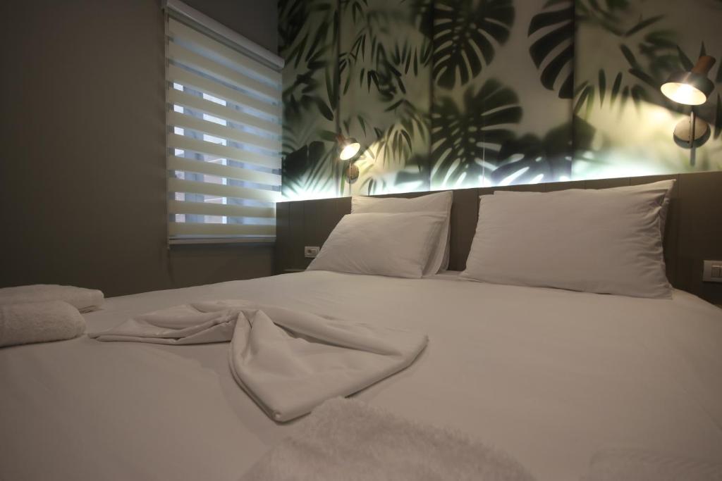 Una cama con sábanas blancas y almohadas en un dormitorio en Alyvia Rooms en Himare