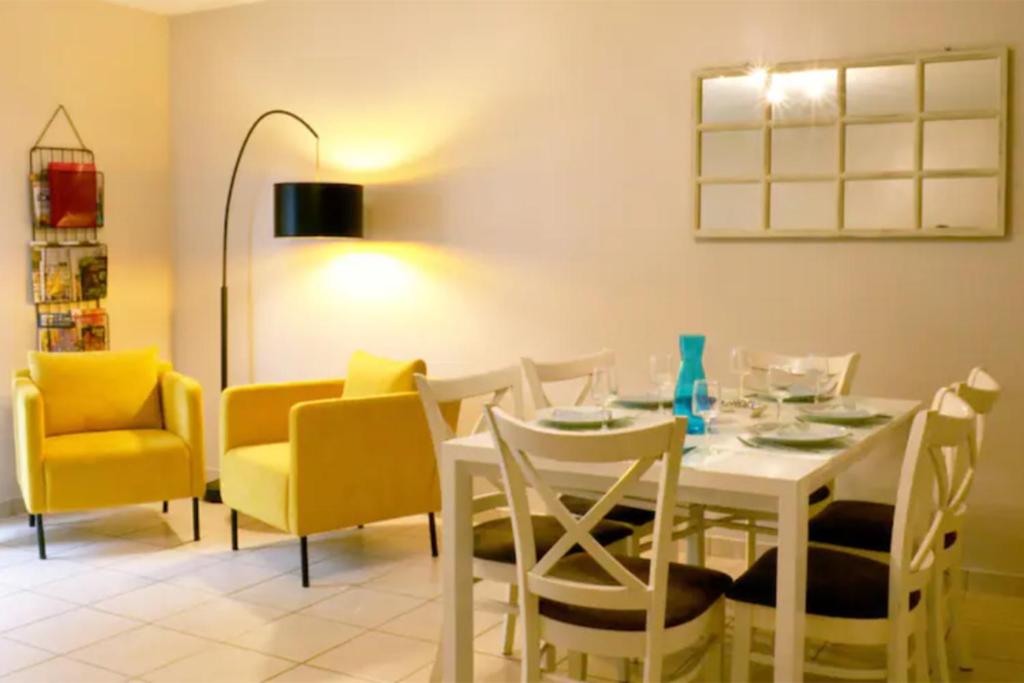 uma sala de jantar com uma mesa branca e cadeiras amarelas em Maison St Eloi by iZiLi *Futuroscope*Jardin* em Poitiers