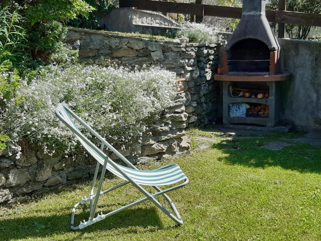 una silla sentada en el césped junto a un horno de piedra en Sauze d'Oulx with garden, ciabot la garitüla - wifi, en Sauze dʼOulx