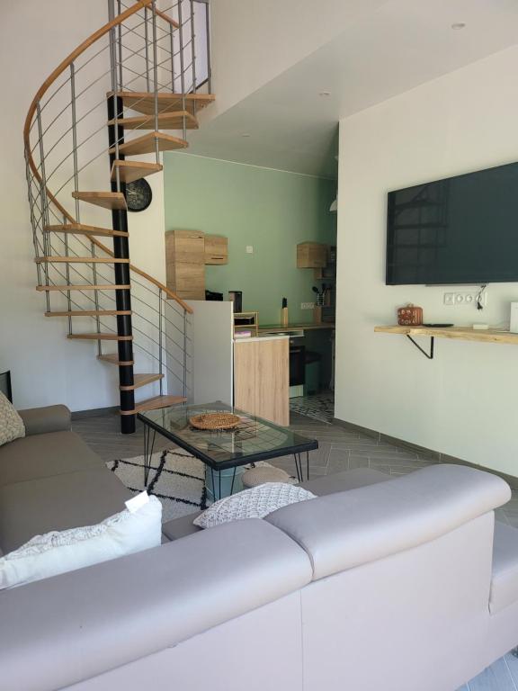 a living room with a couch and a spiral staircase at Le Little cocoon in Durtol