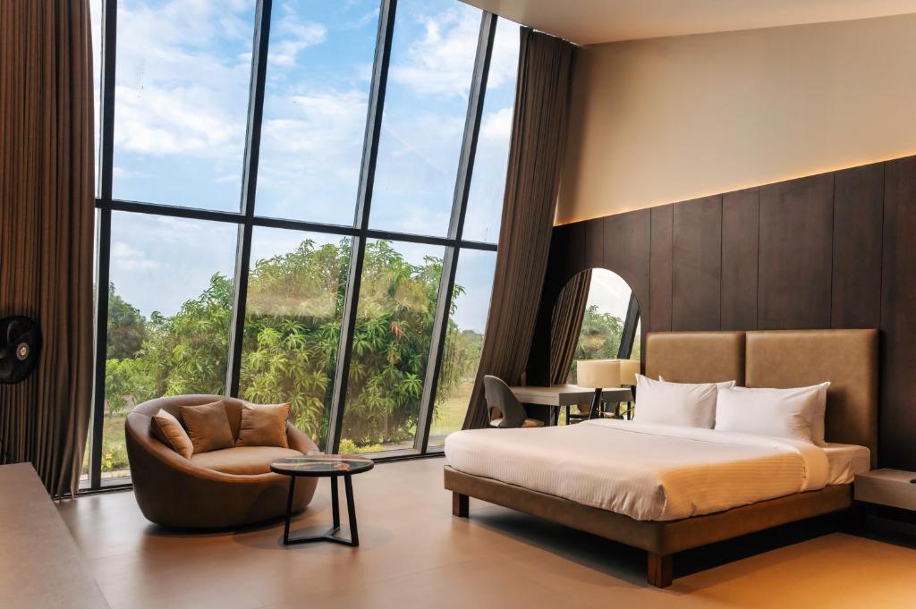 a bedroom with a bed and a chair and a large window at Beyond by Sula in Nashik